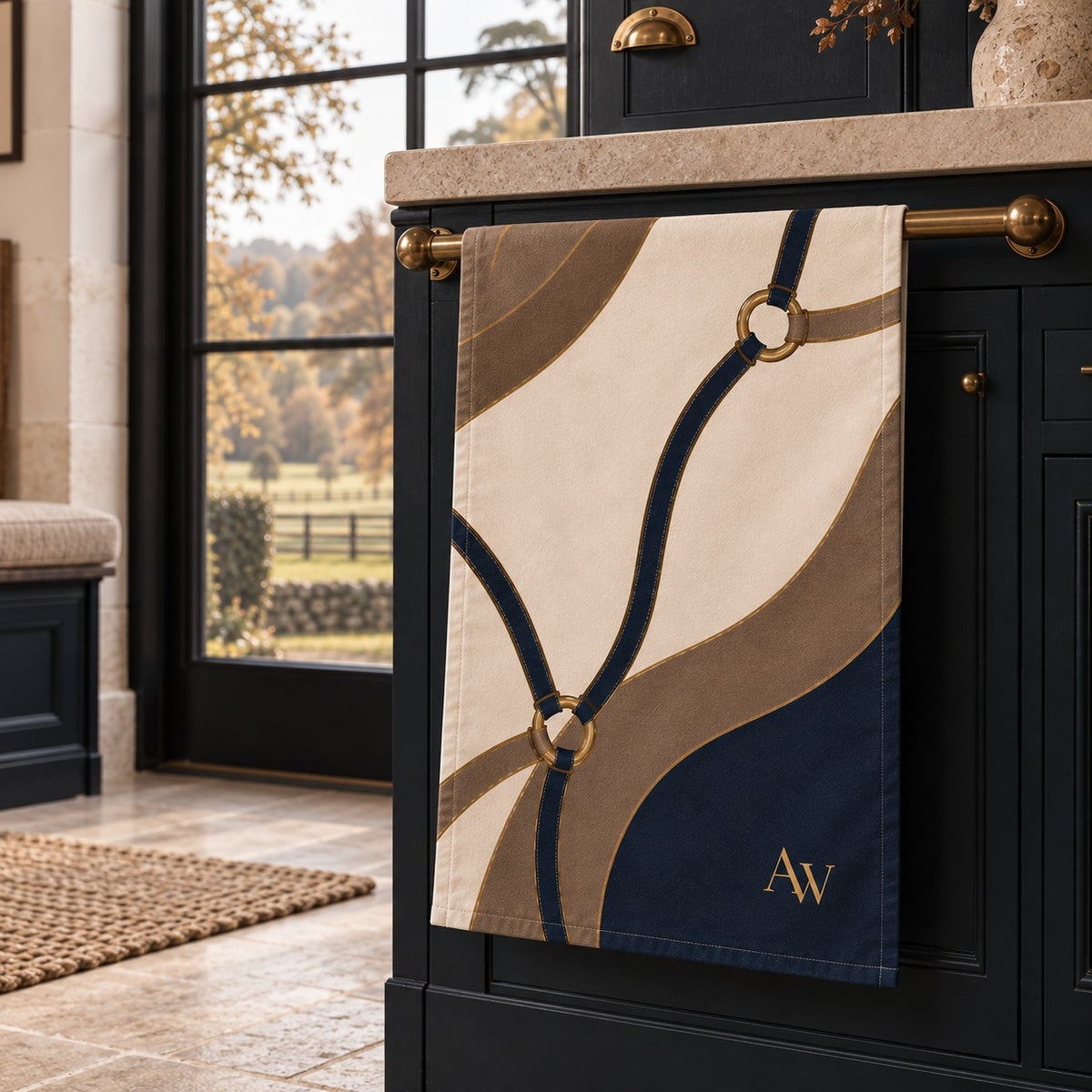 The Reins cotton-linen tea towel with navy and taupe equestrian straps, antique-gold ring details and A&W monogram